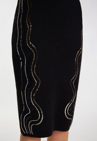 Schwarzer Strick-Minirock mit gewellten, metallischen Paillettenakzenten in Silber, Gold und Schwarz, die ein strukturiertes Design entlang der Seiten schaffen.
