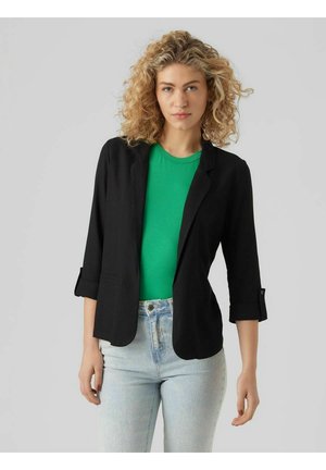 Zwarte blazer met een op maat gemaakte pasvorm, voorzien van opgerolde mouwen en zijzakken, gecombineerd met een groene t-shirt en lichtblauwe jeans.