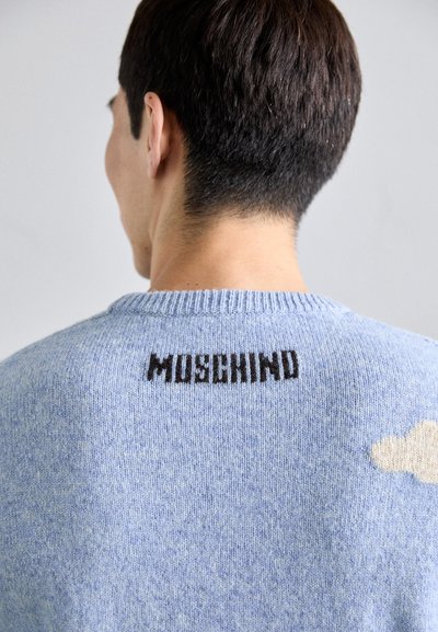 Sinine lõngast kootud kampsun, millel on ümmargune kaelus, tekstuuriga viimistlus ja seljal must "MOSCHINO" logo, millele on lisatud pehme pilvemaaling.