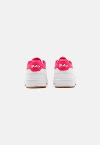 Vita sneakers med rosa textilaccenter vid hälen och vit logotyp. Platt gummisula med gummifärgad bas. Minimalistisk design.