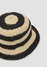 Zwart-beige gestreepte geweven strooien emmerhoed met een ronde kroon en een brede rand, met een gestructureerde afwerking en afwisselende kleurpatronen.