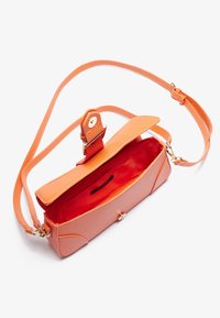 Sac bandoulière en cuir orange avec un design plat, fermeture magnétique et un intérieur rouge vif. Sangle ajustable et texture lisse.