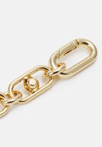 Gouden ketting met een gladde, glanzende afwerking. Bevat een ovale schakel en een ronde connector detail met een sluiting.