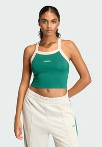 Zelený crop top s krémovými akcentmi a logom "adidas". Vyrobený z elastického materiálu, má široké ramienka a priliehajúci strih.