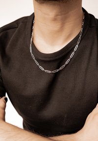Silver chain necklace with elongated links worn over a black ribbed shirt, showcasing a sleek design and shiny metal finish.