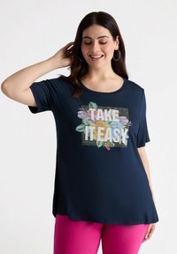 Camiseta de manga corta azul marino con un gráfico floral "TÓMATELO CON CALMA", que presenta impresiones coloridas y acentos brillantes en la parte frontal.