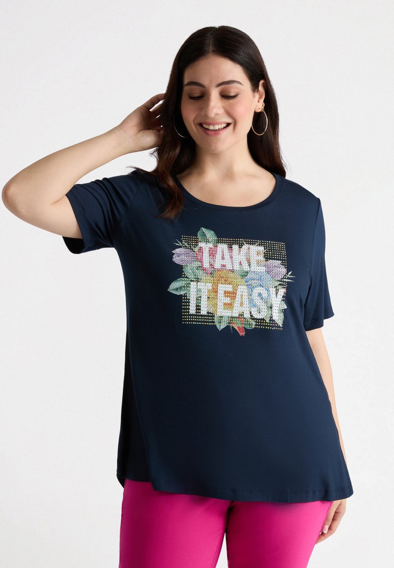 Camiseta de manga corta azul marino con un gráfico floral "TÓMATELO CON CALMA", que presenta impresiones coloridas y acentos brillantes en la parte frontal.