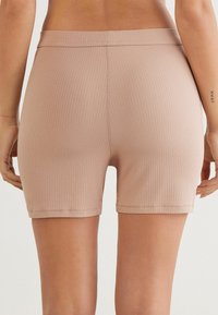 Geribbelde, blushroze shorts met een elastische tailleband, voorzien van een aansluitend ontwerp dat tot halverwege de bovenbenen reikt. Zachte textuur en een nette afwerking.