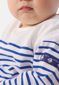 Μπλε και λευκό ριγέ πουκάμισο μακριά μανίκια από απαλό βαμβάκι, με μπλε ταμπελάκι του ναυτικού με γραφικό ιστιοφόρου στο μανίκι.