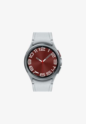 Rundes Smartwatch mit einem burgunderfarbenen Zifferblatt, weißen Stundenmarkierungen und einer silbernen Lünette. Sie hat ein weißes Silikonarmband mit strukturierten Akzenten.