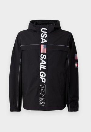 Black jacket with a hood, featuring a central white stripe with "USA SAIL GP TEAM" text and American flag emblem; includes zippered pockets.