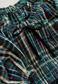 Groen, rood en wit geruite blouse van stof met een gathered taille, met een zwarte fluwelen strik en elastische hals. Merkenlabel: NEXT.