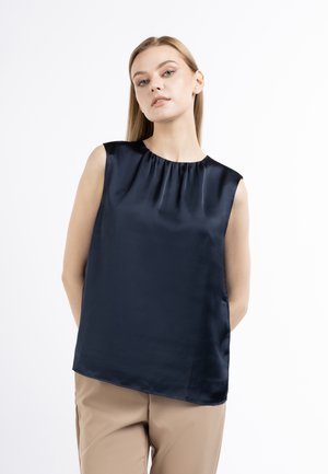 Mørkeblå satin blus uden ærmer med sammensnørede åbning, glat tekstur og løs pasform, parret med beige bukser. Minimalistisk design.