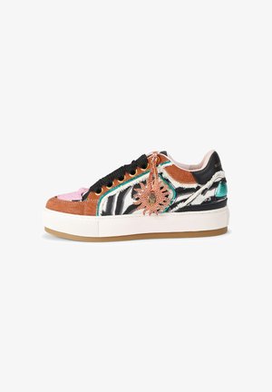 Platformsneaker met zwart-wit zebrapatroon, bruin suède, roze en turquoise accenten, zwarte veters en een decoratieve bronzen zonnenhanger.