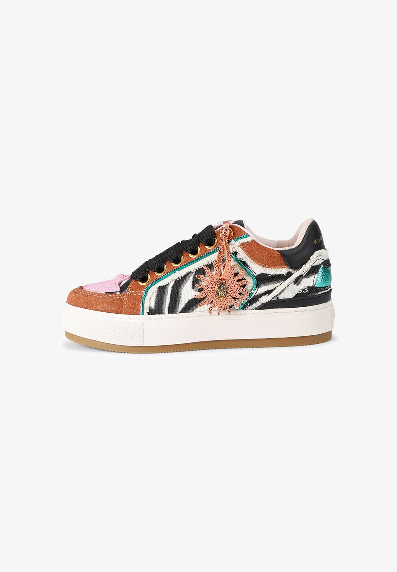 Platform sneaker with black and white zebra pattern, brown suede, pink and teal accents, black laces, and a decorative bronze sun charm.