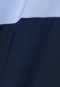 Tissu bleu et marine avec une texture côtelée, présentant un design en blocs de couleur. La section supérieure est bleu clair, tandis que la section inférieure est bleu foncé.