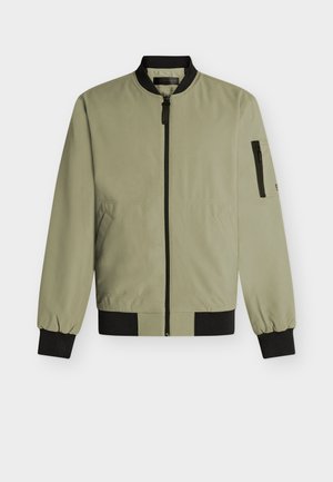 Giacca bomber verde oliva chiaro con colletto, polsini e orlo neri, cerniera frontale, due tasche laterali e tasca con cerniera sulla manica sinistra.