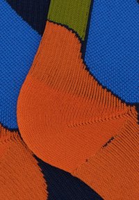 Calzini colorati con sezioni di blu, arancione, verde e blu navy, caratterizzati da un motivo a maglia testurizzato e punte di colore contrastante.