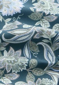 Blumenstoff mit einem dunkelblauen Hintergrund und hellblauen sowie cremefarbenen Blumen und Blättern. Weiche Textur mit filigranen Details und Mustern.