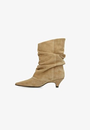 Tan suede slouchy mid-calf boot with pointed toe and low kitten heel, shown in side profile on white background.