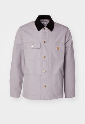 Lichtgrijze katoenen jas met een zwart corduroy kraag, twee zijzakken en bronzen knopen. Heeft een logo patch op de borstzak.