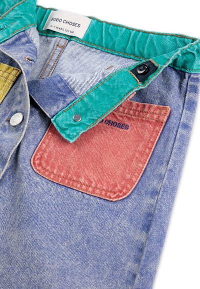 Chemise en denim avec un col turquoise, des patchs jaunes et rouges, et une étiquette portant la mention "BOBO CHOSES" avec des boutons pression en métal argenté.
