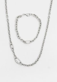 Set de colier și brățară din metal argintiu, prevăzut cu inele ovale interconectate și un închizător tip homar sigur. Textură netedă și design simplu.