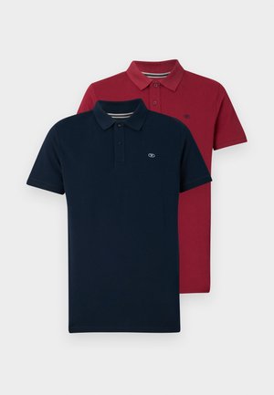 Dve polo majice: ena v mornarsko modri, ena v burgundski. Obe imata klasičen ovratnik, zapenjanje na tri gumbe in izšito logotip na prsih.