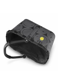 Bolso tote negro con textura suave, presenta un patrón gris de caritas sonrientes, un acento amarillo y un robusto asa negra. Pequeño bolsillo con cremallera en el interior.