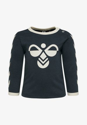 Mørkeblå langærmet skjorte med cremefarvede detaljer; har et stort cremefarvet logo i midten og mønstrede ærmer med zigzag-detalje.