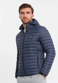 Granatowa puchowa kurtka z kapturem, charakteryzująca się poziomym pikowaniem, bocznymi kieszeniami na zamek i małym logo na klatce piersiowej. Gładka tekstura.