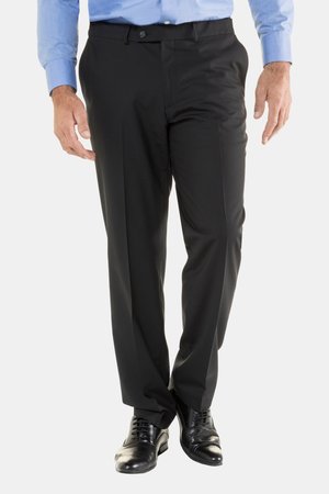 Mann trägt schwarze Anzughose, schwarze Anzugsschuhe und ein hellblaues, langärmeliges Hemd, das in die Hose gesteckt ist, und steht vor einem weißen Hintergrund.