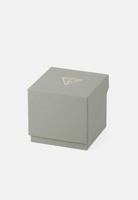 Grå texturerad presentask med en triangelformad guld-logotyp på toppen. Fyrkantig form, design med gångjärnslock, minimalistisk estetik.