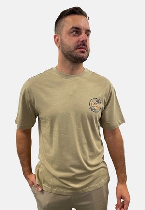 Beige T-Shirt mit kurzen Ärmeln, gefertigt aus weichem Stoff, mit einem kleinen schwarzen grafischen Design mit floralem Motiv auf der linken Brust.