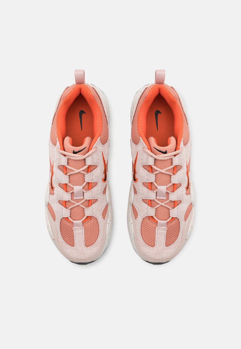 Un par de zapatillas Nike en rosa y naranja con detalles de malla y gamuza, vista superior, mostrando los logotipos negros de Nike en el interior y en el lateral.