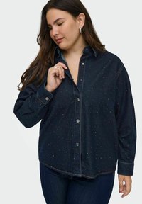 Dark denim shirt featuring a button-down front, long sleeves, and subtle speckled detailing. Classic collar and cuffed sleeves.