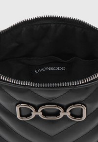 Černá prošívaná kabelka z umělé kůže se stříbrným řetízkovým detailem a zipovým uzávěrem, s černou látkovou podšívkou a štítkem s logem.