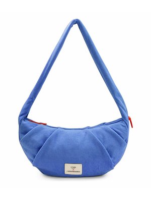 Sac à main bleu doux en forme de croissant avec une large bandoulière rembourrée et une petite étiquette rectangulaire de marque à l'avant.