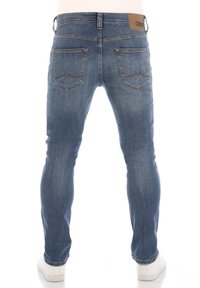 Jeans in denim skinny-fit in un lavaggio azzurro chiaro, con una superficie tessurizzata, due tasche posteriori con dettagli di cucitura e una patch in pelle marrone sul cinturino.