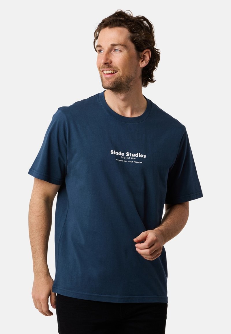 Merineilinen puuvillainen t-paita, jossa on pyöreä kaula-aukko ja lyhyet hihat, etupuolella valkoinen logopaino. Sujuva pinta.