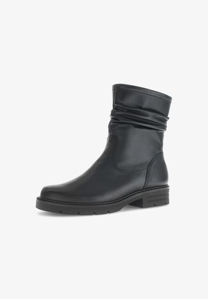 Bottine en cuir noir avec un haut décontracté, bout arrondi et semelle texturée. Présente des coutures minimalistes et un faible talon carré.