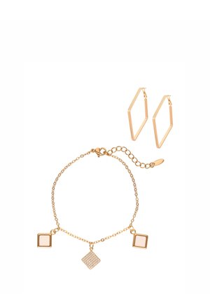 Złota bransoletka z kwadratowymi zawieszkami oraz para geometrycznych złotych kolczyków kołowych na białym tle.