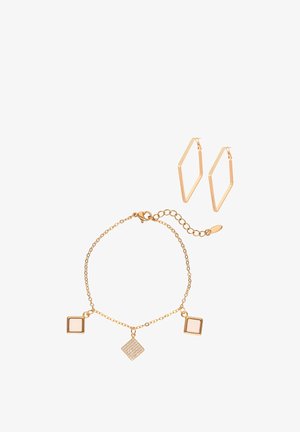 Złota bransoletka z kwadratowymi zawieszkami oraz para geometrycznych złotych kolczyków kołowych na białym tle.
