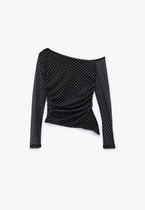 Haut noir à manches longues avec un design dénudé sur les épaules ; présente des pois blancs, un côté froncé et une texture de tissu lisse.