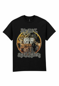 Zwarte katoenen t-shirt met een grafisch ontwerp van een spookhuis en een figuur. Tekst "BLACK SABBATH" in een witte en oranje cirkelvormige achtergrond.