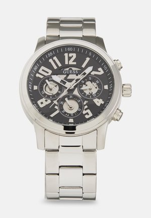 Montre en acier inoxydable argenté avec un cadran noir, de grands chiffres blancs, trois sous-cadrans et un bracelet en maillons métalliques. Comprend une couronne et des poussoirs.