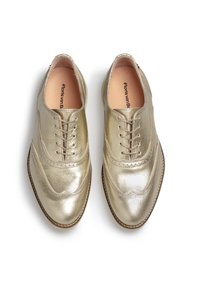 Scarpe oxford in pelle dorata con finitura lucida, design a punta d'ala e lacci beige; presentano una punta arrotondata e dettagli di cucitura sottili.