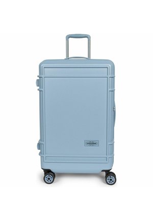 Valise rigide bleu clair avec quatre roues pivotantes, poignée rétractable et logo Eastpak à l'avant.