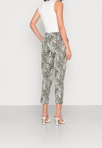 Kalhoty vyrobené z lehkého materiálu s zeleno-bílým vzorem palmových listů. Zkrácený střih, elastický pas a doplněné o bílé podpatky.