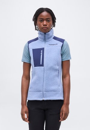 Asmuo dėvi šviesiai mėlyną vilnos liemenę su užtrauktuku krūtinės kišenėje ant trumpomis rankovėmis marškinių, stovintis priešais baltą foną.